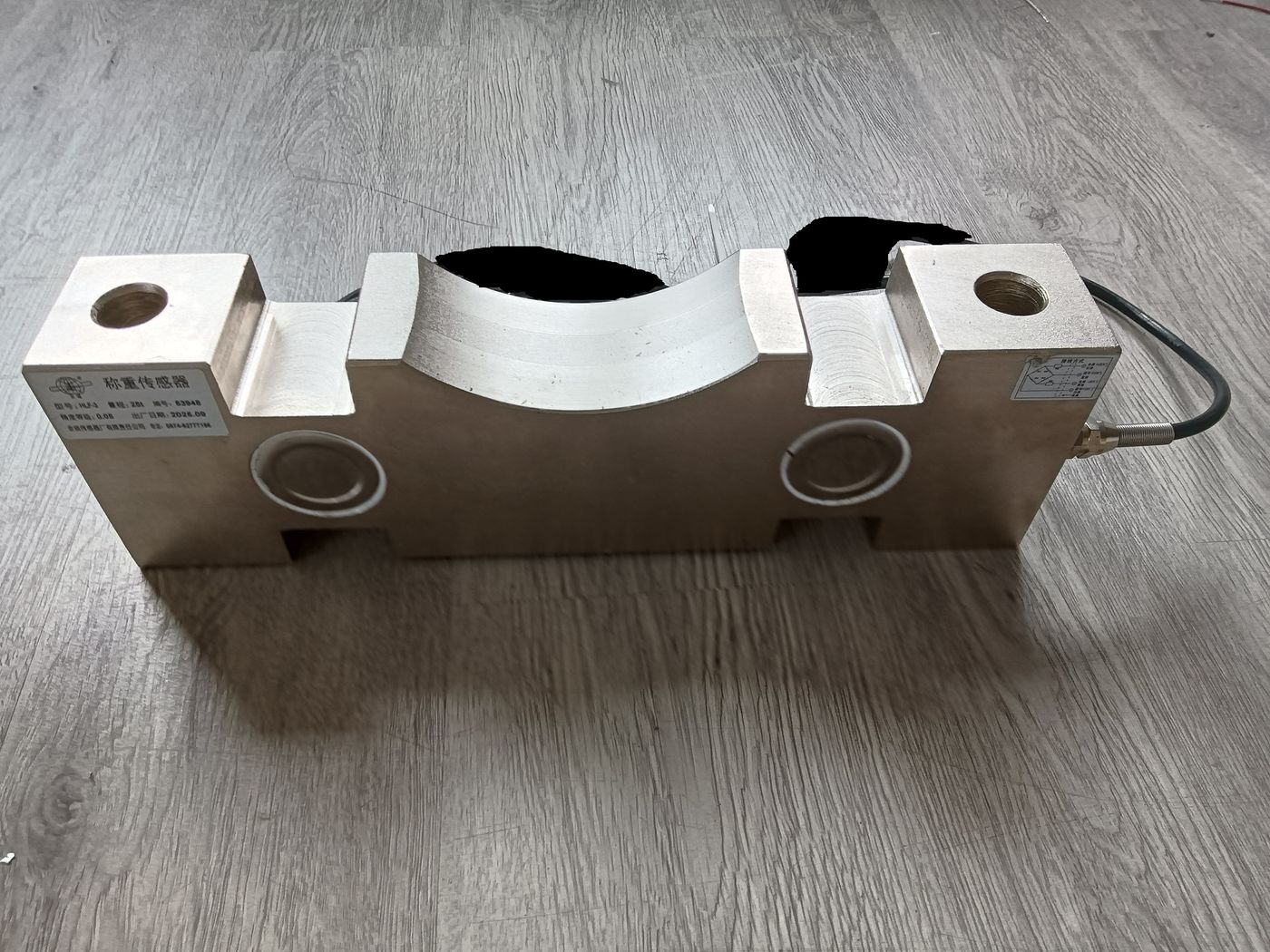 Aluminium bending cell on a wooden floor with a curved relief in the middle and mounting bores at each end