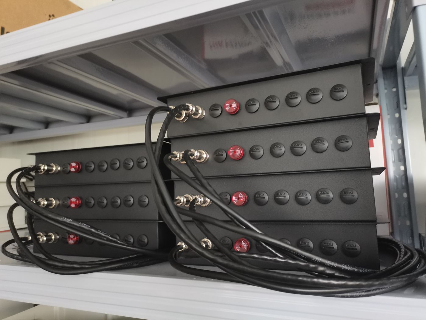 Stacked black collector panels on a shelf, each with a row of round ports and a red cap, cables coiled in front