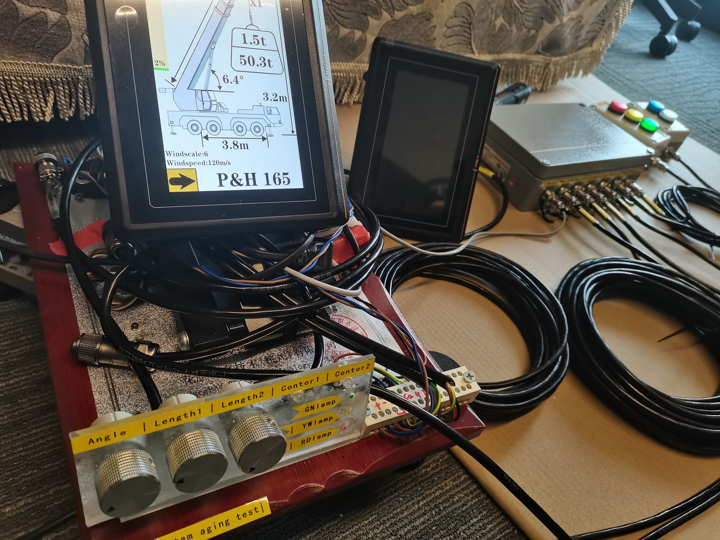 Two terminals and a collector box on a desk, with a red test board carrying three knobs and channel labels in front