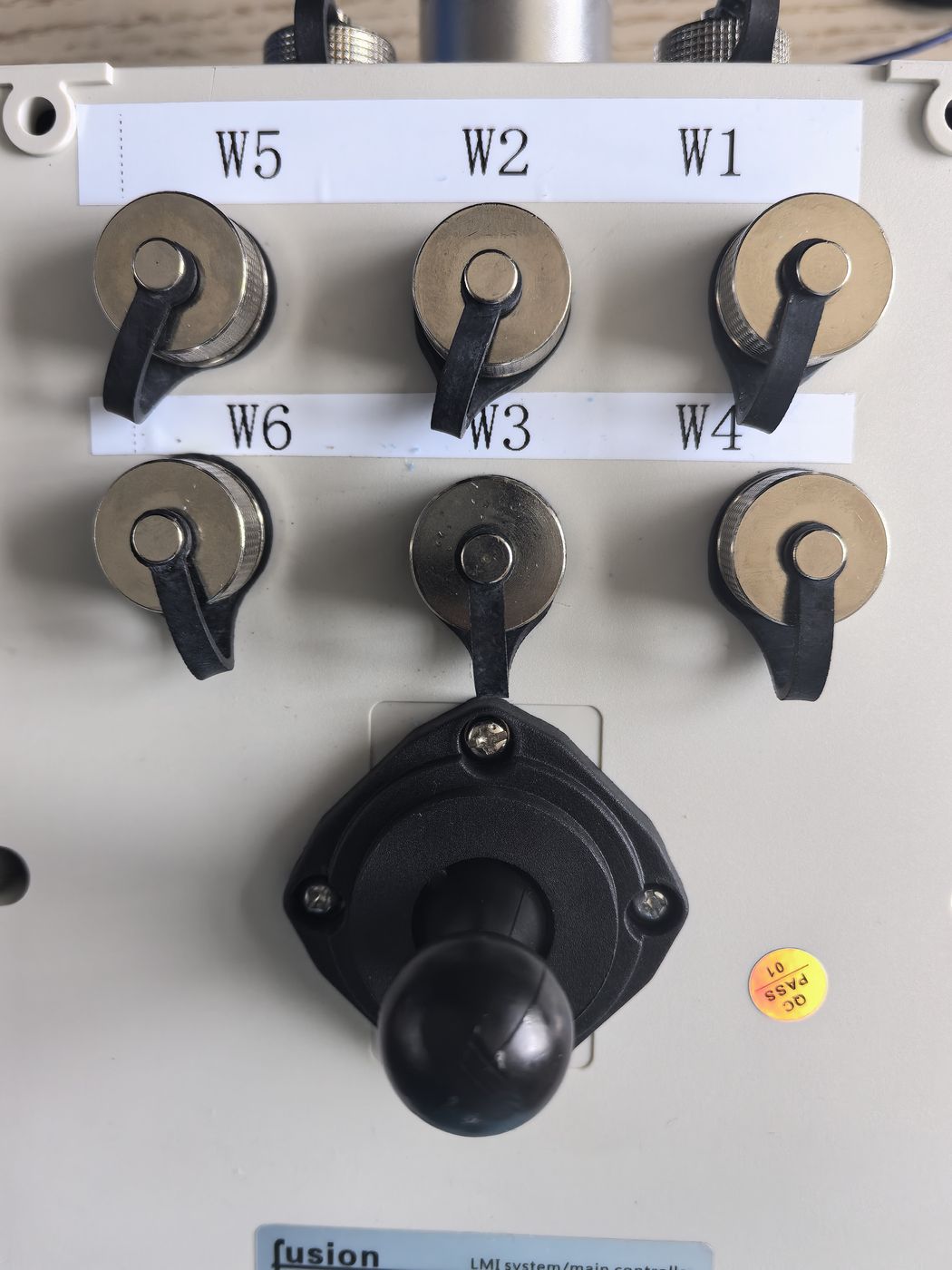 Six metal knobs on a white operation plate labelled W5, W2, W1, W6, W3 and W4, with a black cross lever below