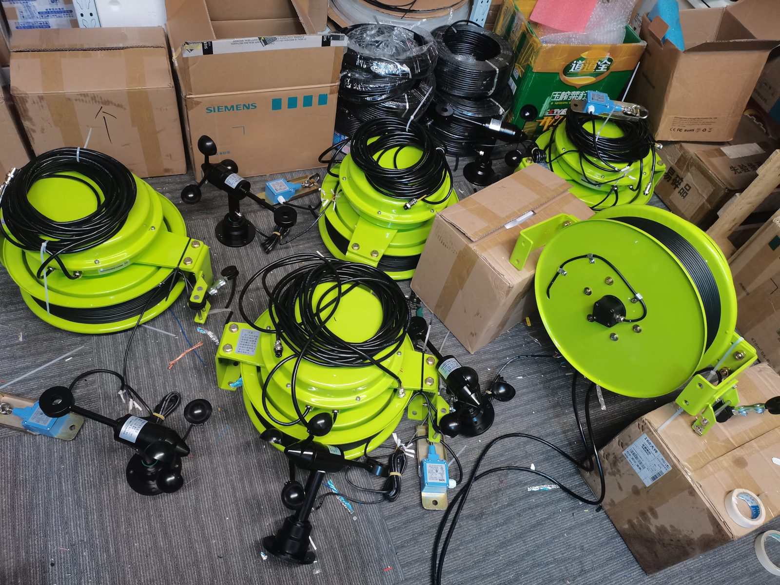 Green draw-wire reels with coiled cable arranged on a workshop floor