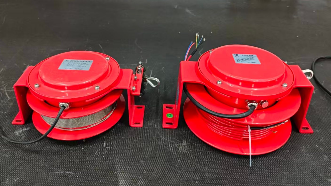 Two red draw-wire length sensors side by side showing cable entry