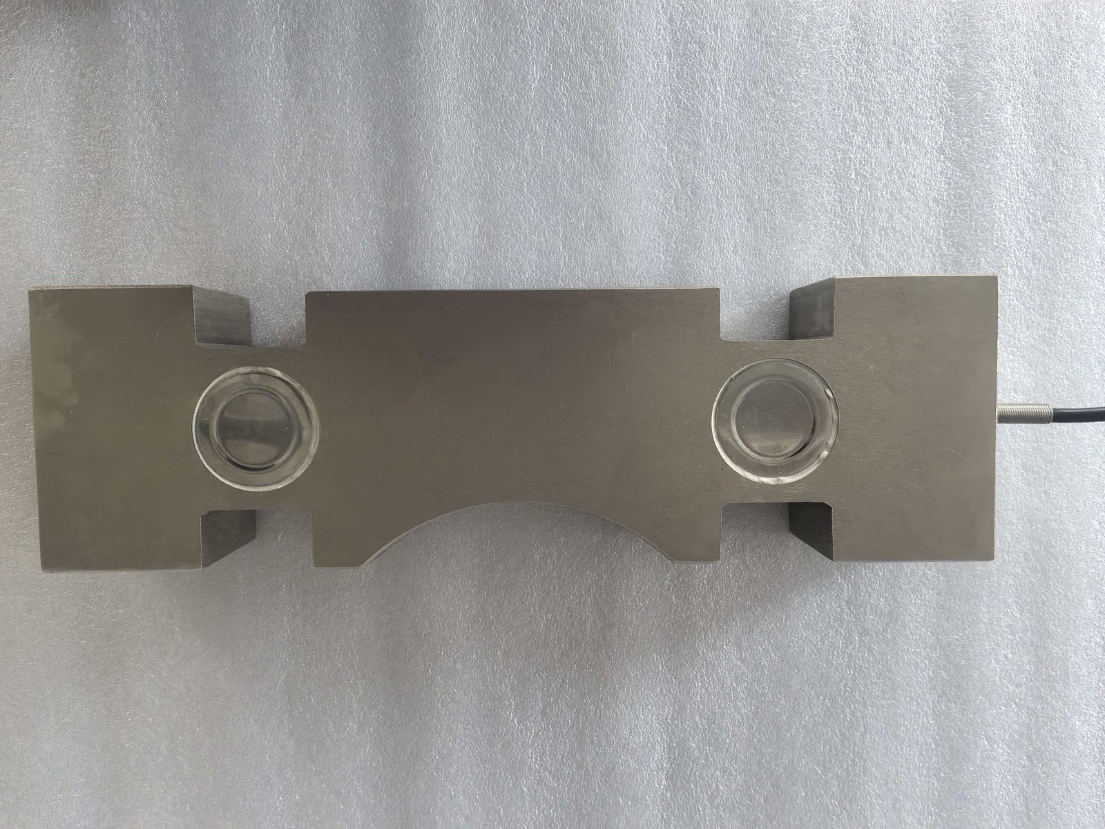 Stainless block-type load cell on a white surface