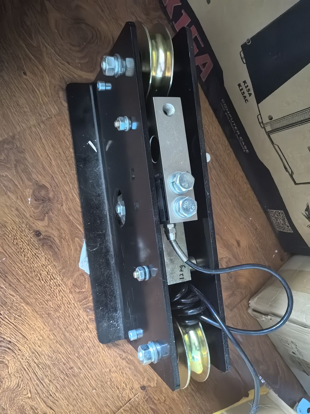 Black plate frame on a wooden floor with yellow sheaves at each end and a cell with its lead fixed in the middle