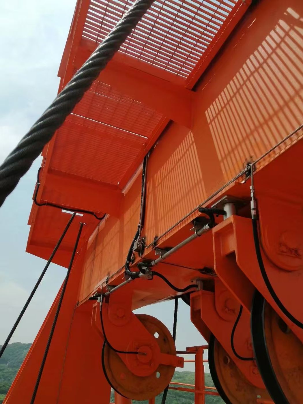 Orange portal and slew structure seen from below, wire rope dressed along the steelwork with sensor leads visible