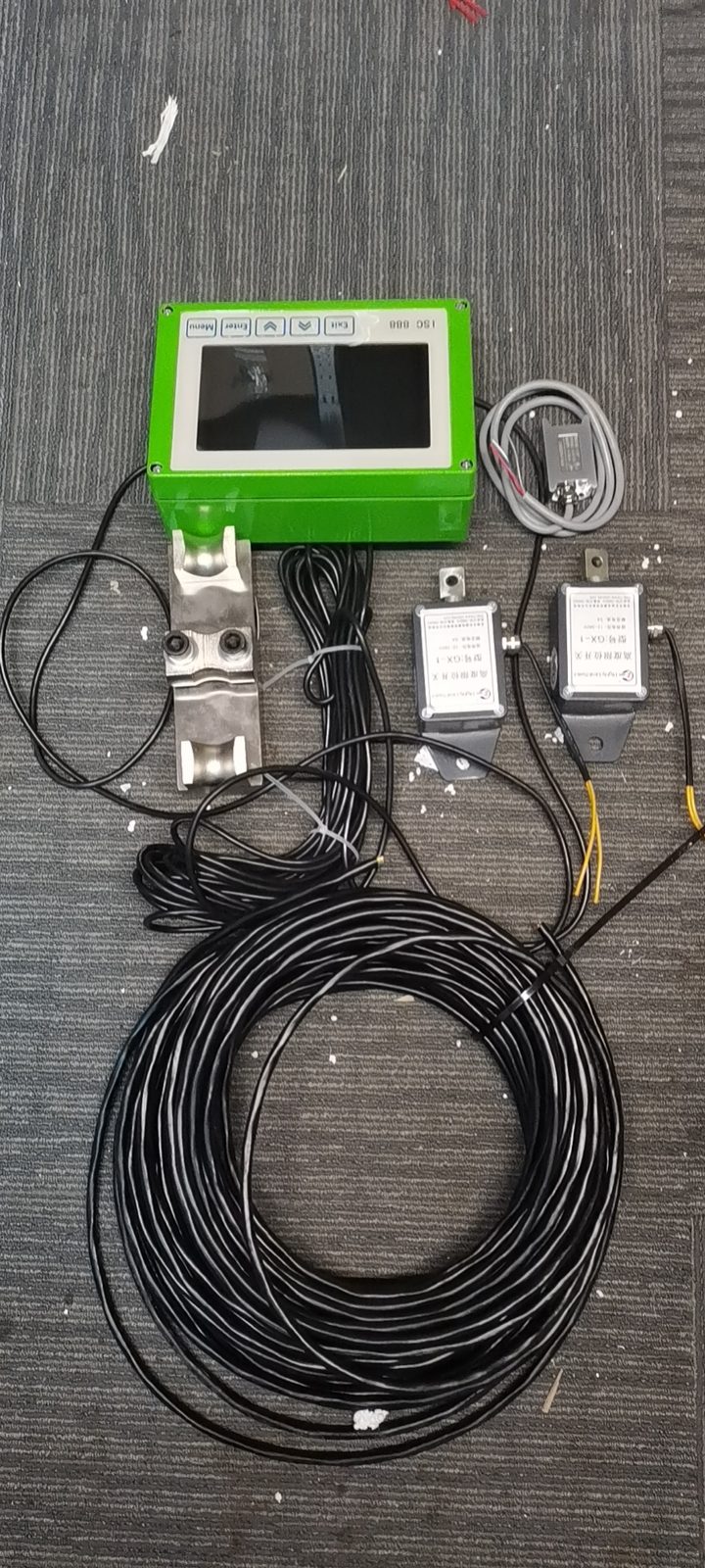 Green terminal with load cells and a coiled cable on a mat