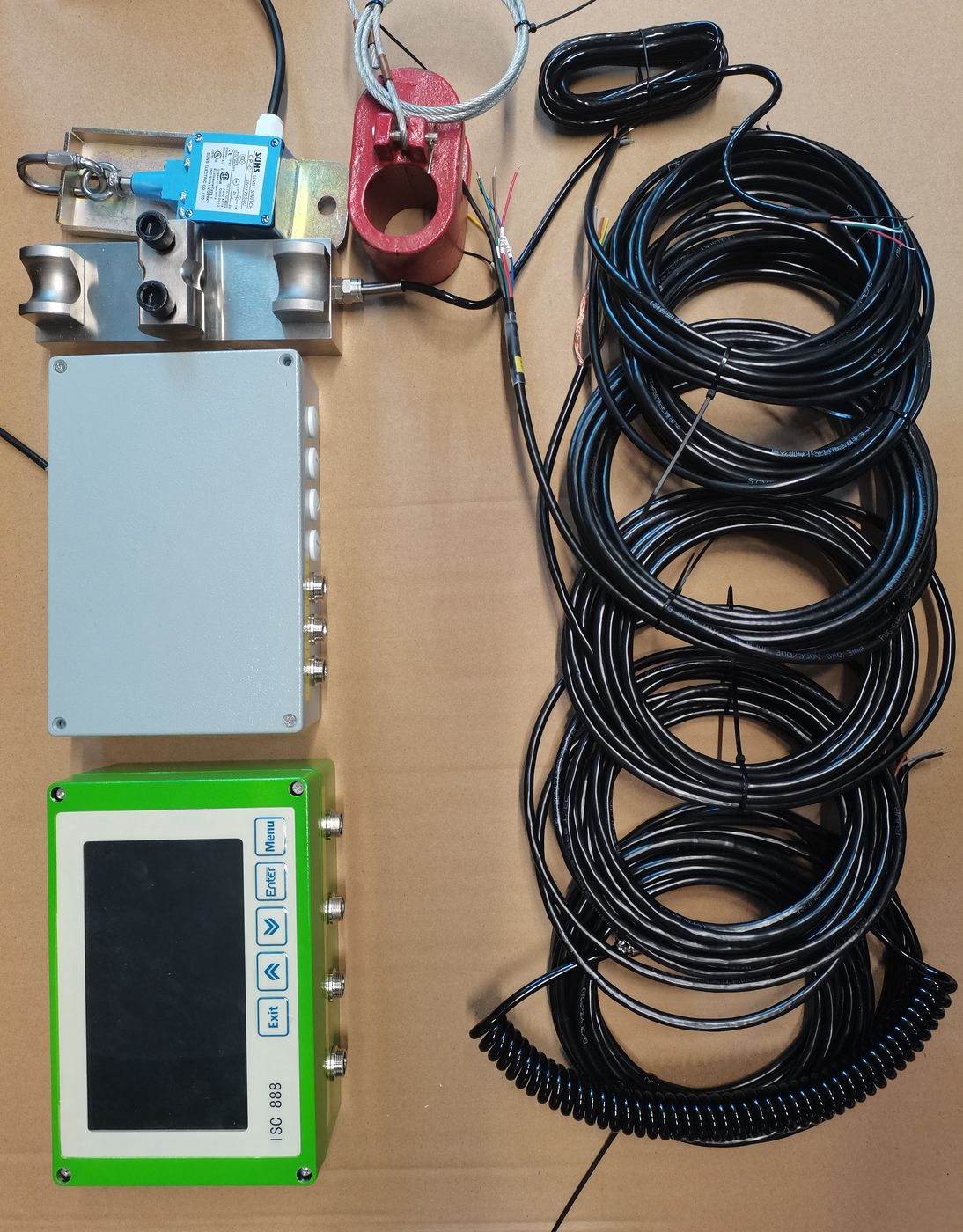 Blue box, shackles, grey collector, green terminal and one large coil of black cable laid on cardboard