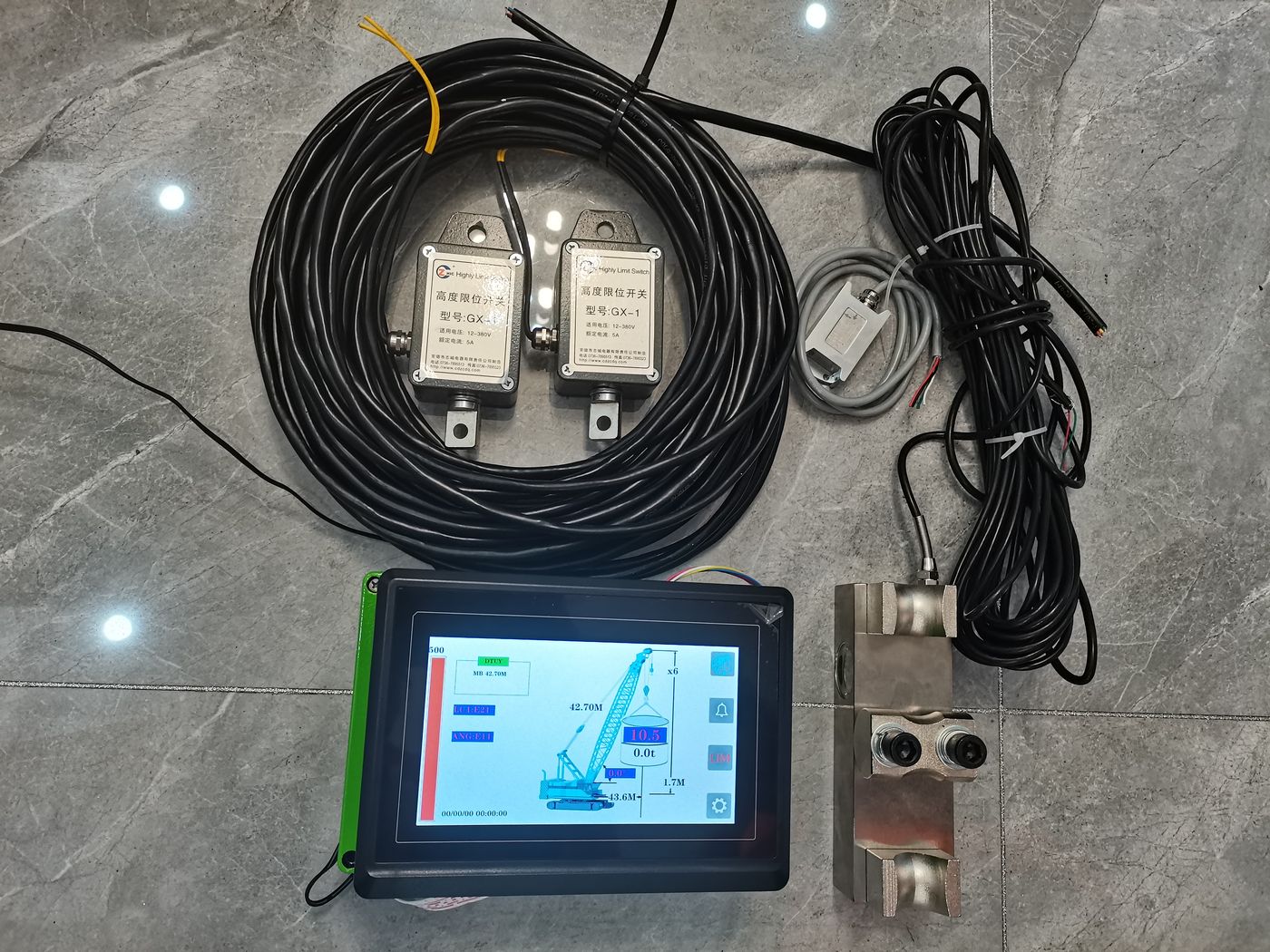 Two coiled cable runs, two labelled cells, a machined part and a green-edged terminal on tiles