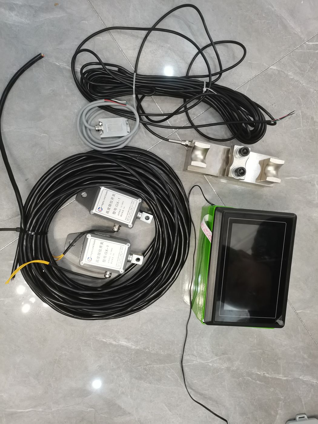 One large cable coil, two labelled cells, a small grey coil and a green-housed terminal on tiles