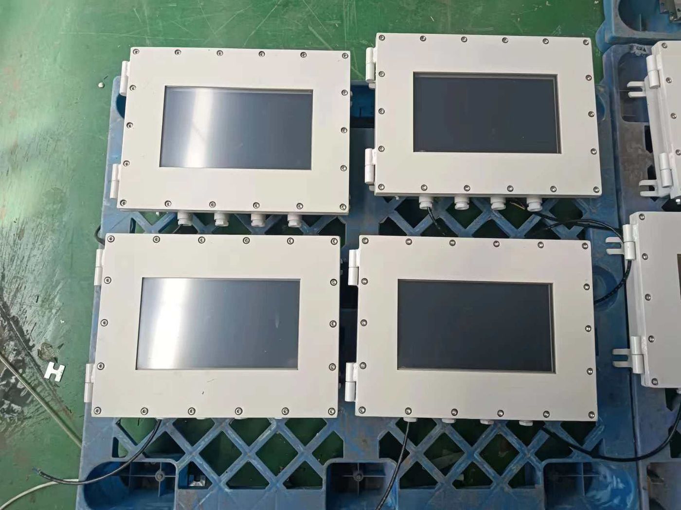 Four white-housed terminals with screens up, standing side by side on a blue pallet