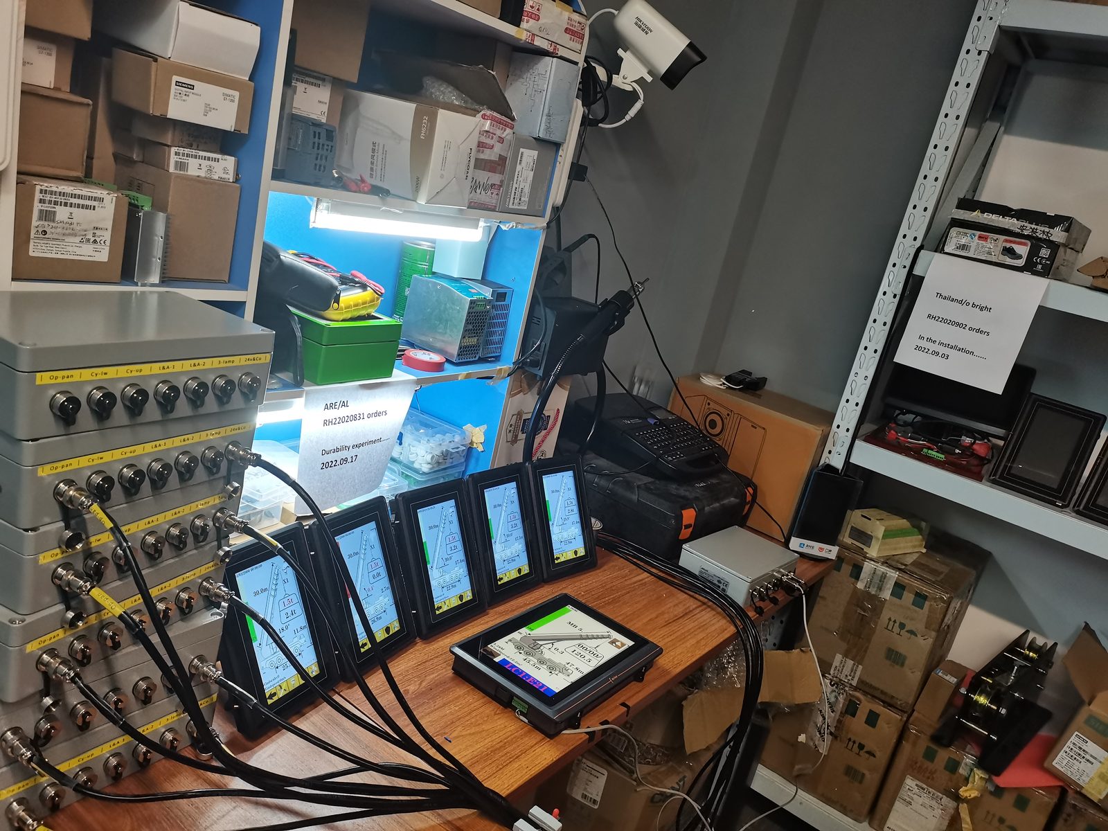 Row of terminals powered on a workshop bench with boxes behind