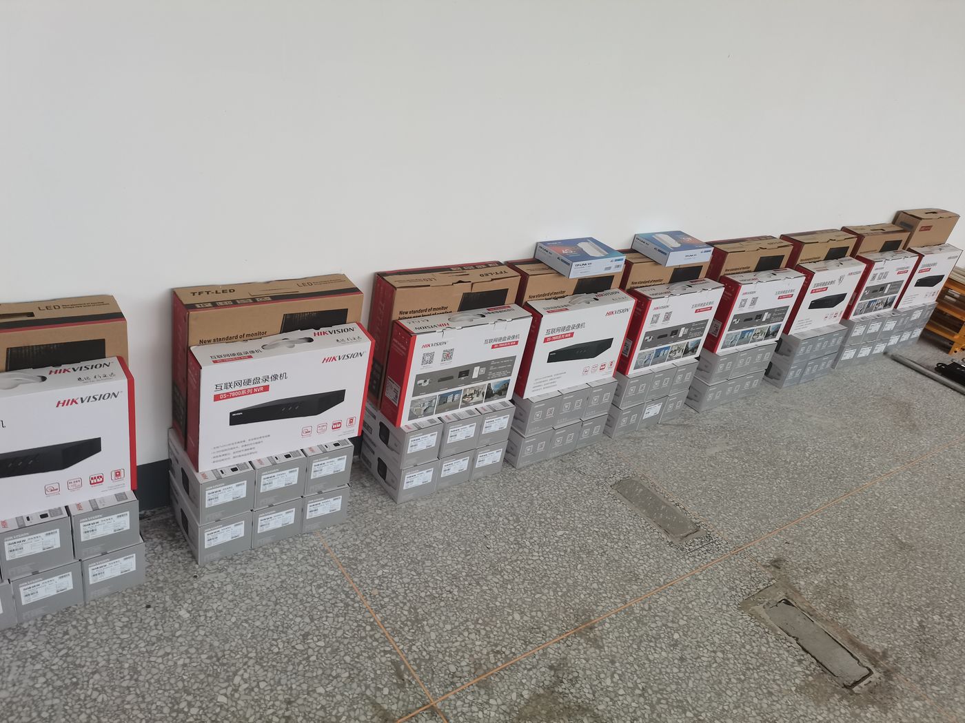 A row of red and white cartons stacked neatly on a concrete floor with small boxes on top