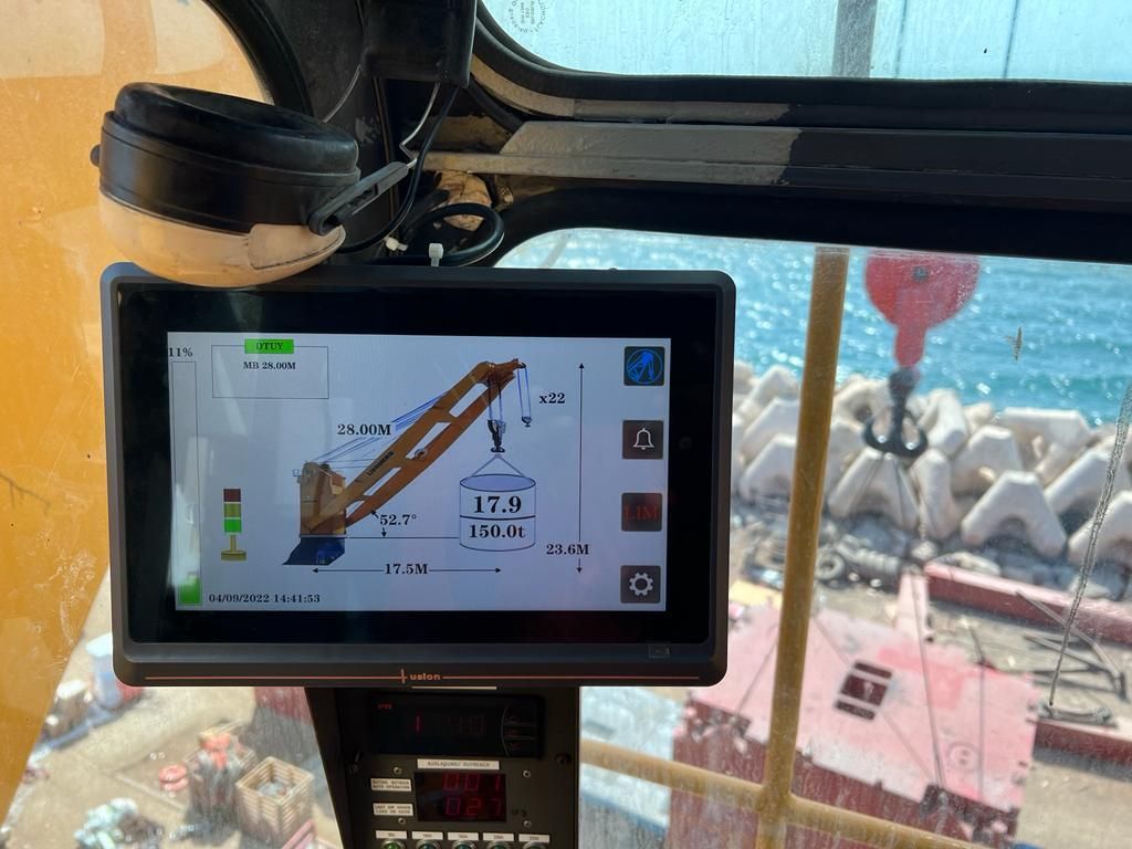 Crane console screen showing live load data with a quayside beyond